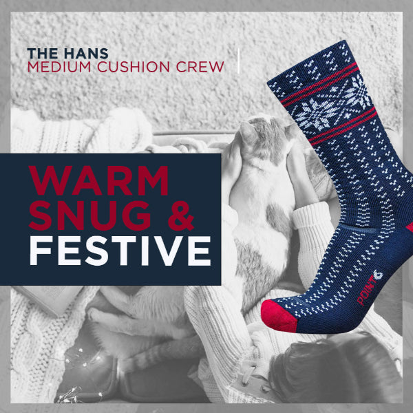 Blue and red patterned sock with text 'The Hans Medium Cushion Crew Warm Snug & Festive' on a gray background.